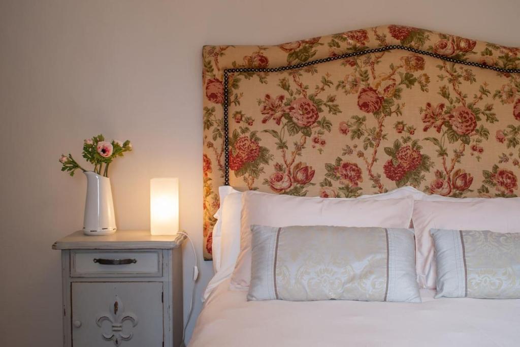 a bed with a floral headboard and a table with a lamp at 11 Deerpark Drive East in Cape Town