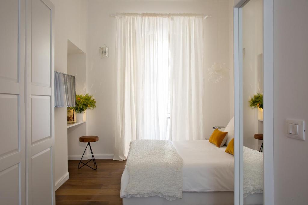 ein weißes Schlafzimmer mit einem Bett und einem Fenster in der Unterkunft Domus Sansevero in Neapel