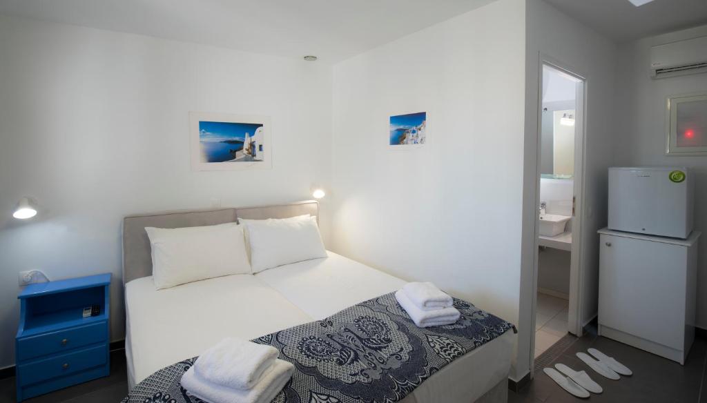 a small bedroom with a white bed and a refrigerator at Edem in Fira