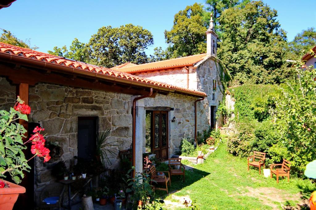 uma antiga casa de pedra com um jardim e uma igreja em Pazo de Chaioso em Maceda