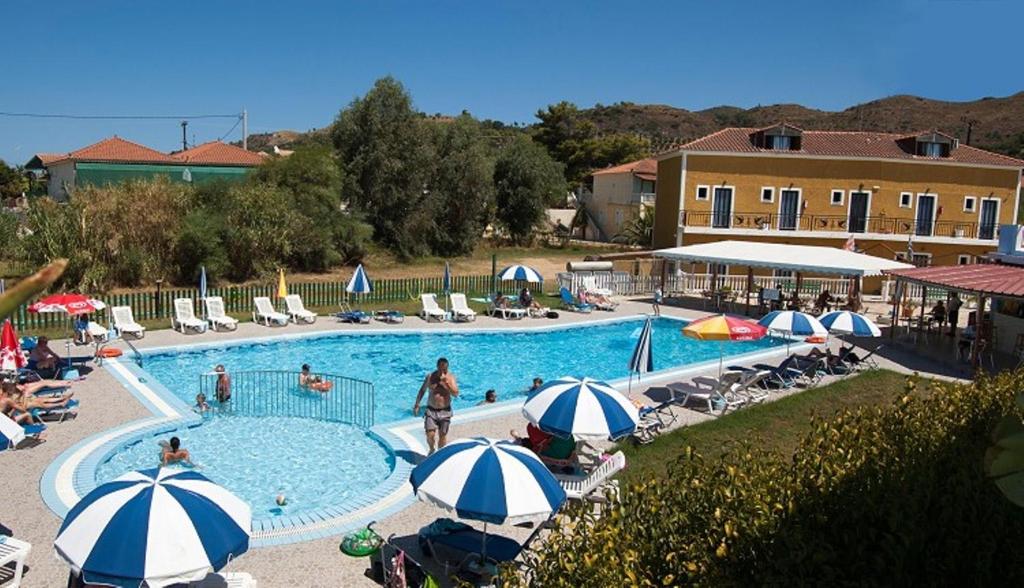 a swimming pool with umbrellas and people sitting around it at Plubis Studios in Kalamaki