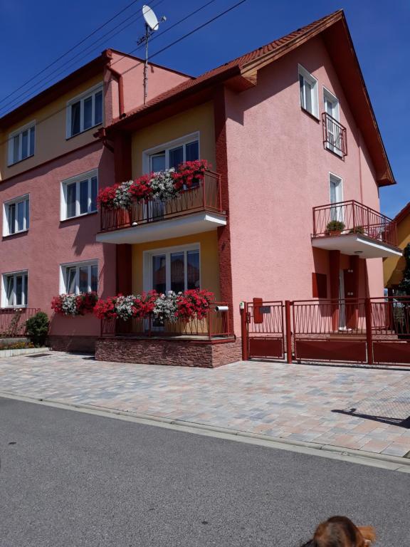ein rosafarbenes Gebäude mit Blumenkästen auf den Balkonen in der Unterkunft Apartmány BOSS in Liptovský Mikuláš