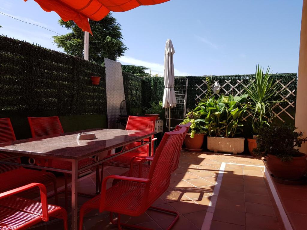 Casa en Peligros cerca de Granada في بيليغروس: فناء مع كراسي حمراء وطاولة مع مظلة