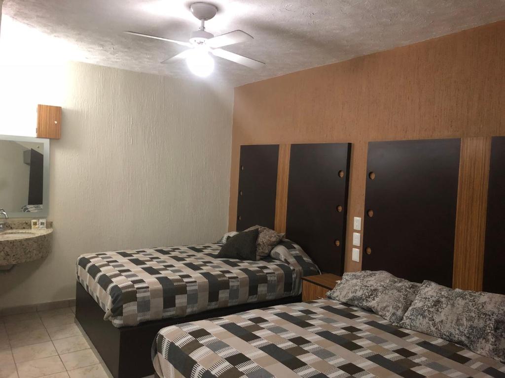 a bedroom with two beds and a ceiling fan at Hotel del Carmen in León