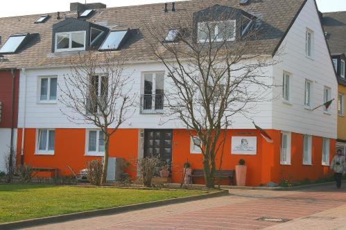 una gran casa blanca y naranja con árboles delante de ella en Aqua Marina en Helgoland