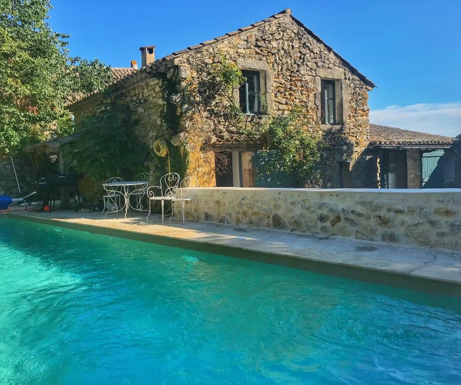 una casa con tavolo e sedie accanto a una piscina di La Magnanerie d'Audabiac a Lussan