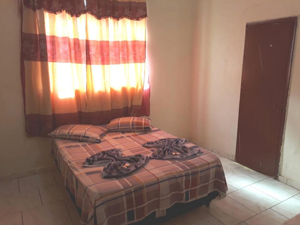 1 dormitorio con 1 cama con manta y ventana en Hotel Santa Marta, en Ribeirão Preto