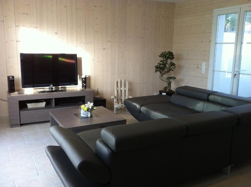 a living room with a couch and a tv at La Fleur de Sel in La Flotte