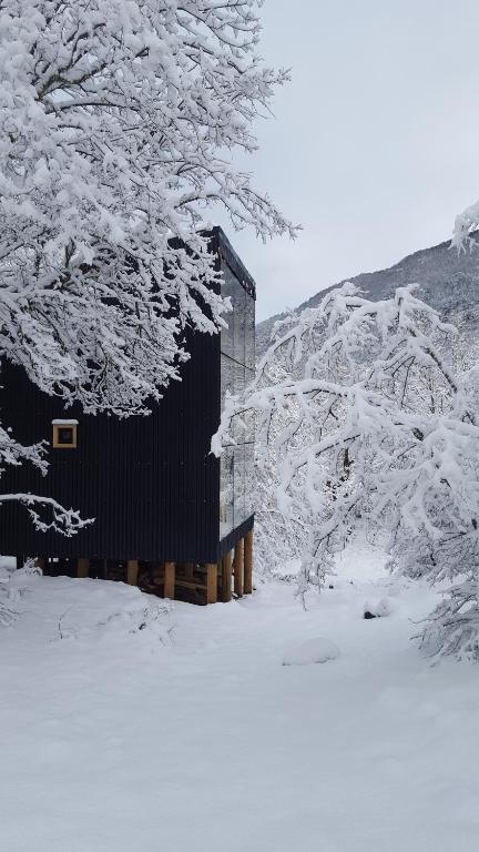 una cabaña en la nieve con árboles nevados en Andrómeda Lodge, en Las Trancas