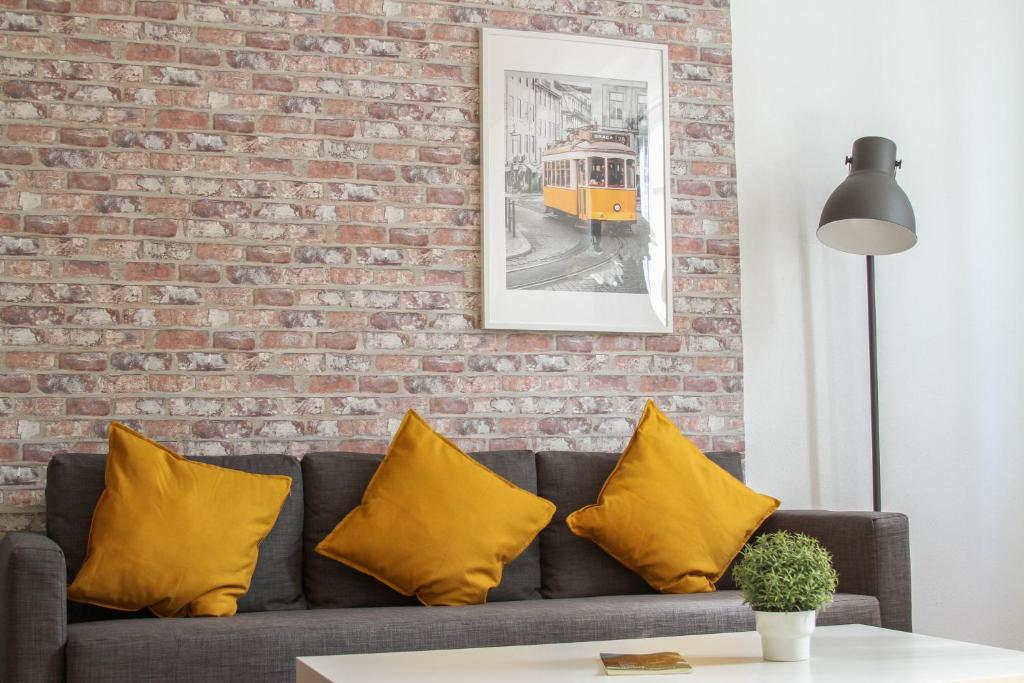 カスカイスにあるComfortable apartment in Cascaisのレンガの壁(ソファ、黄色の枕付)