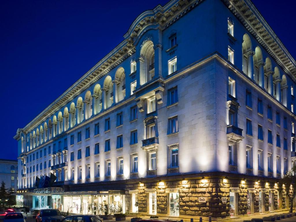 a large white building at night with lights at Sofia Balkan Palace in Sofia