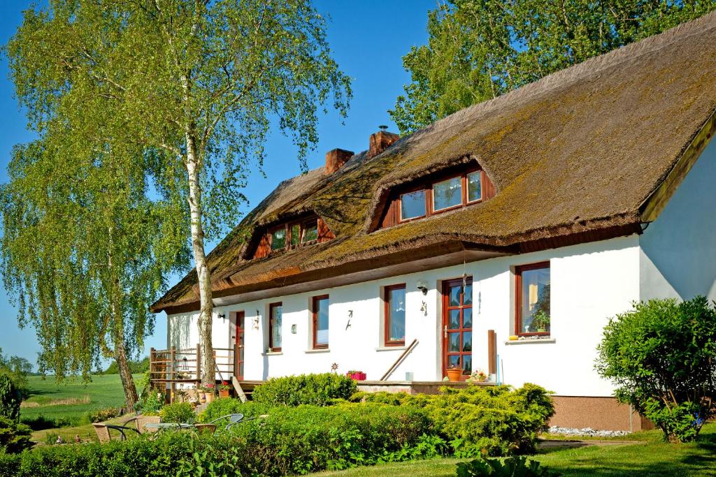 ein großes weißes Haus mit einem Strohdach in der Unterkunft Landhaus Vilmblick in Putbus