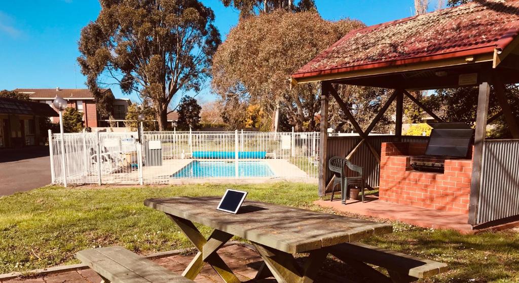 a person sitting on a bench next to a pool at Alfred Motor Inn in Ballarat
