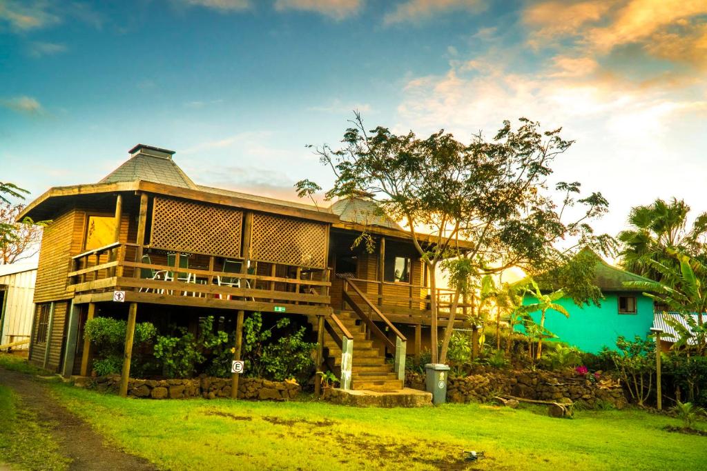 a large wooden house with a porch and a yard at Cabañas Tokerau in Hanga Roa