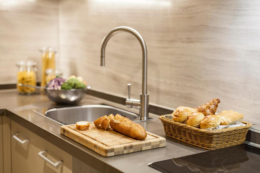 a kitchen counter with a sink and a basket of bread at Ascott Riverside Garden Beijing in Beijing