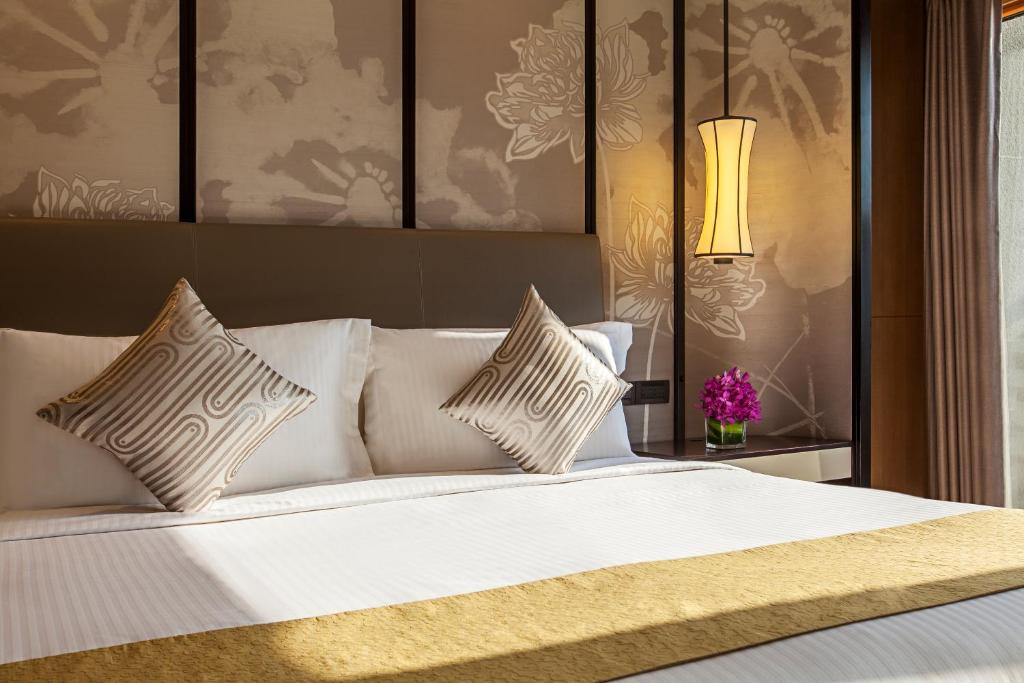 a bedroom with a white bed with pillows and a lamp at Ascott Riverside Garden Beijing in Beijing