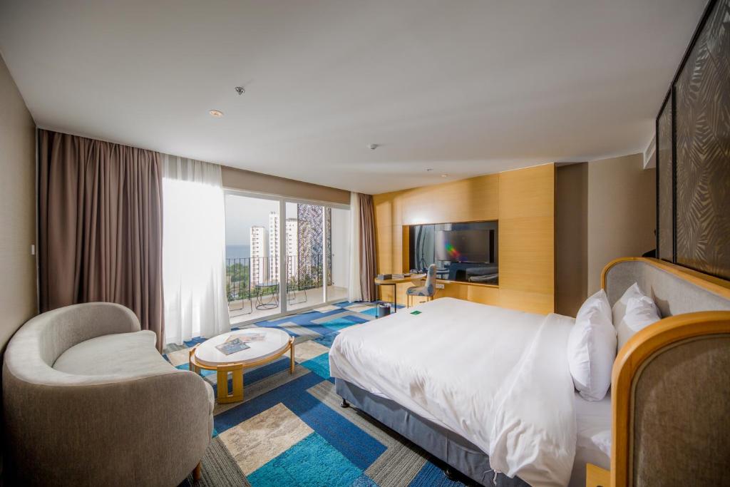 a hotel room with a bed and a chair and a television at Quinter Central Nha Trang in Nha Trang