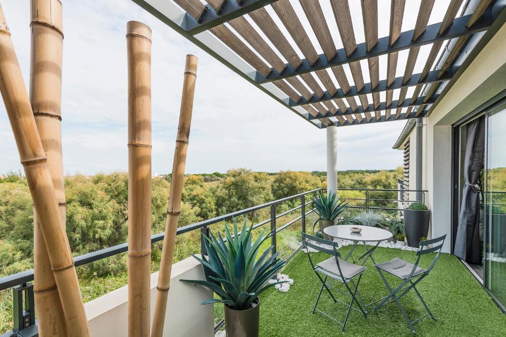 d'une terrasse avec une table et des chaises sur un balcon. dans l'établissement Appartement de L'Espiguette, au Grau-du-Roi