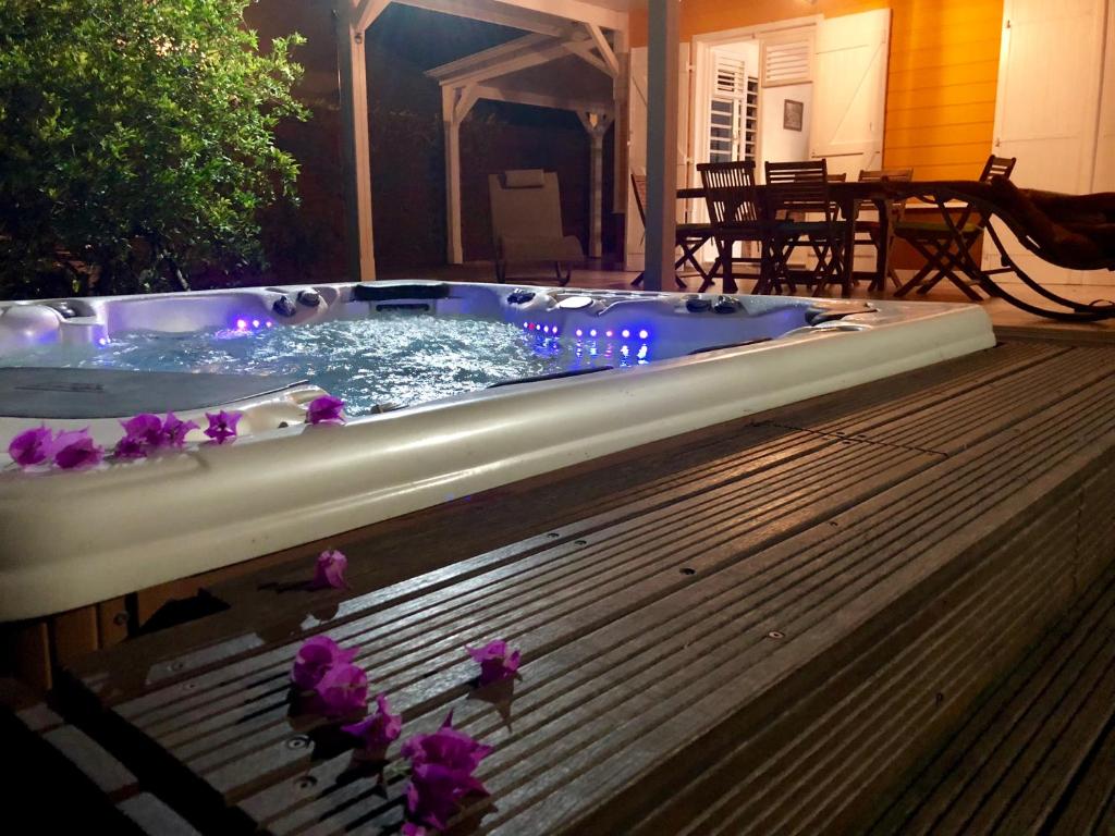 una vasca idromassaggio su una terrazza con fiori viola di La Villa Des Tropiques - Turquoise a Les Trois-Îlets