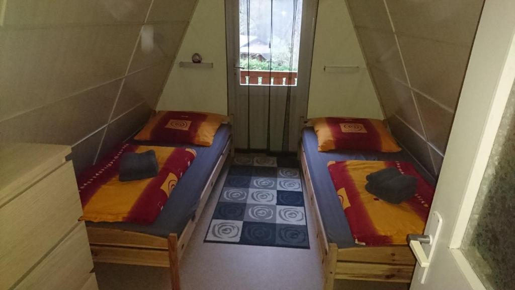 2 Betten in einem kleinen Zimmer mit Fenster in der Unterkunft Ferienhaus Zum See in Perlin