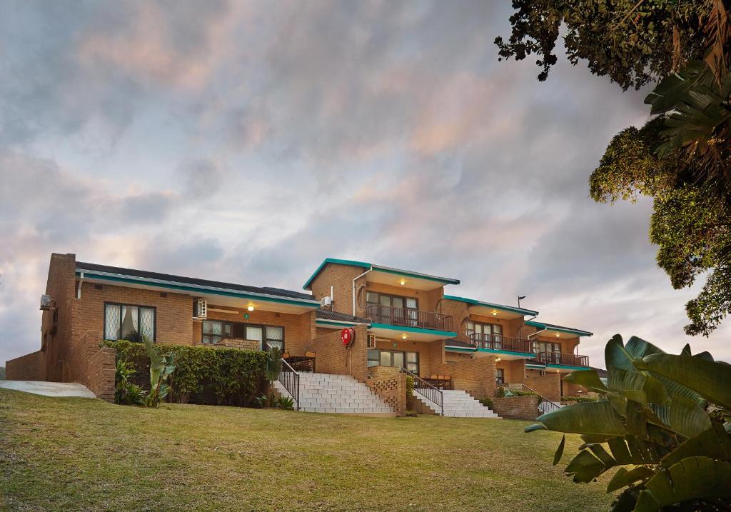 un gran edificio de ladrillo con césped delante en First Group Club Hacienda, en Shelly Beach