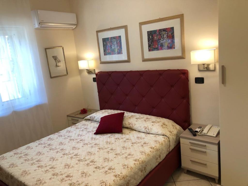 Schlafzimmer mit einem Bett mit rotem Kopfteil in der Unterkunft B&B Primerano SP73 in Soriano Calabro