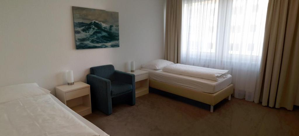 ブレーマーハーフェンにあるNordsee Apartmentsのベッドルーム1室(ベッド1台、椅子、窓付)