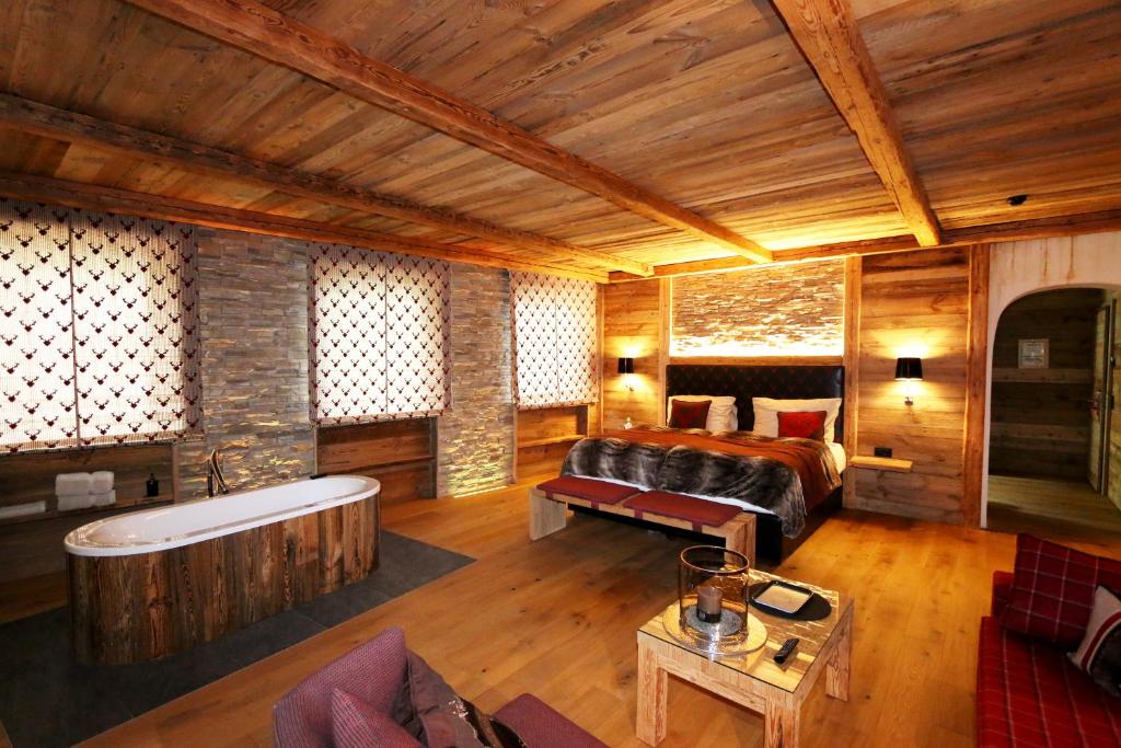 a bedroom with a bed and a tub in a room at Amber Ski-in/out Hotel & Spa in Saas-Fee