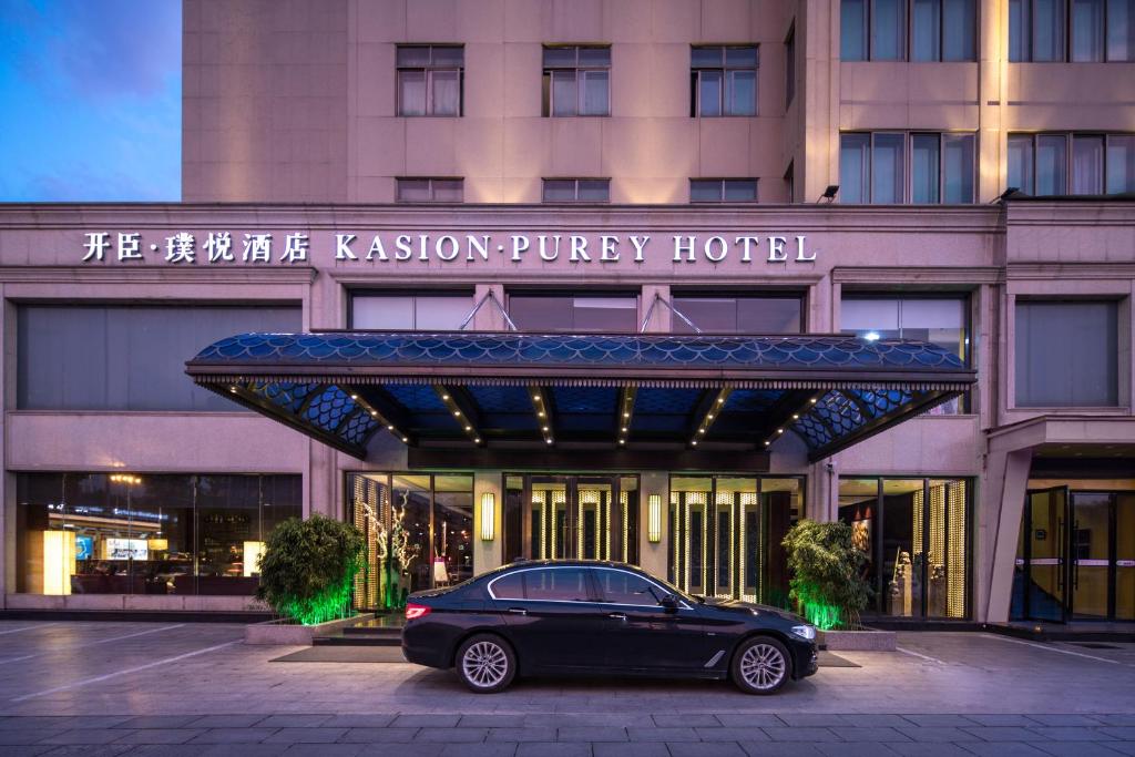 un coche aparcado frente a un hotel en Yiwu Kasion Purey Hotel, en Yiwu