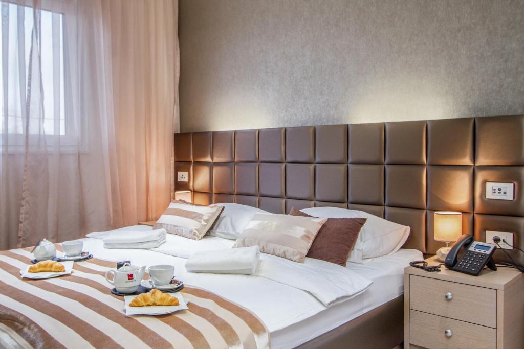 a large bed with two plates of food on it at Royal Airport Hotel in Velika Gorica