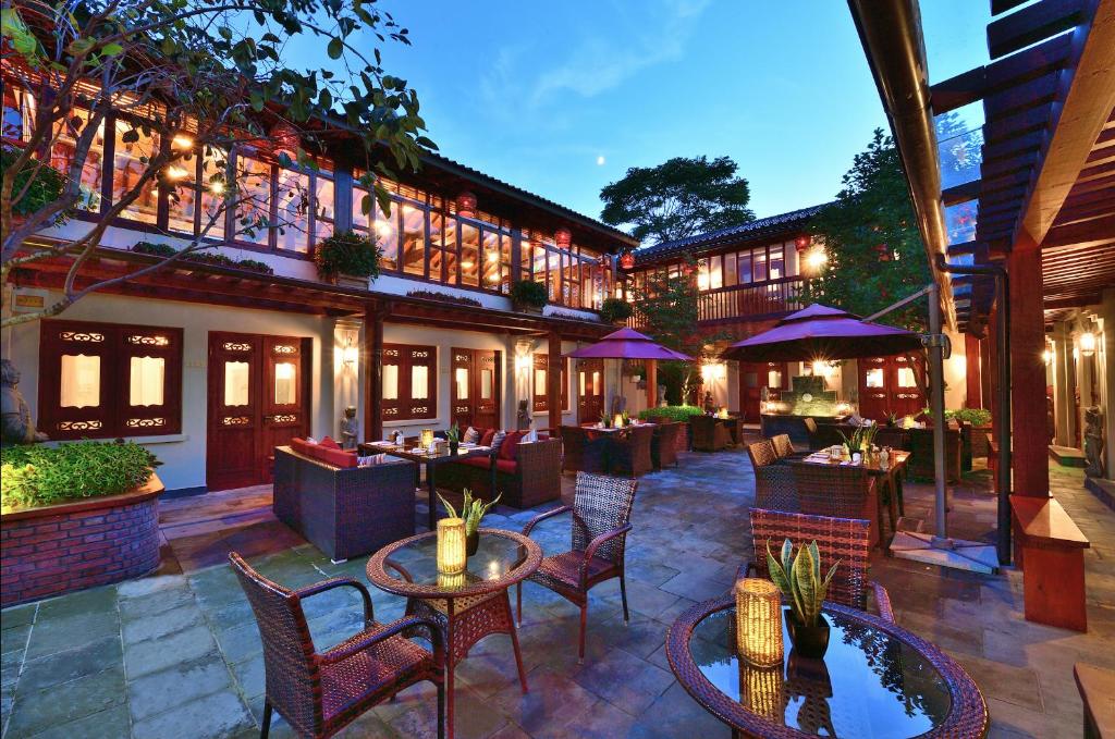 eine Hotelterrasse mit Tischen, Stühlen und Sonnenschirmen in der Unterkunft Jingshan Garden Hotel in Peking