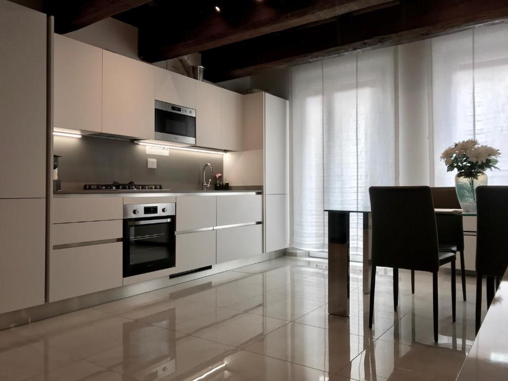 une cuisine avec des placards blancs et une table avec des chaises dans l'établissement Moderno affaccio su via Mazzini, à Ferrare