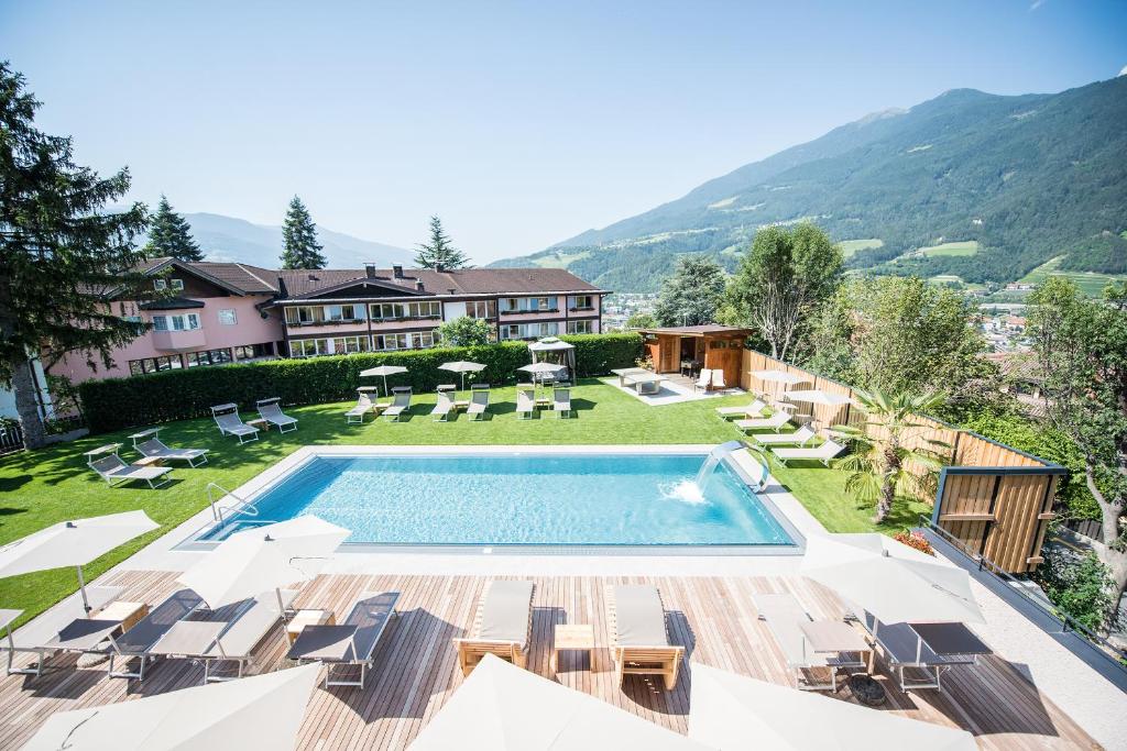 a house with a swimming pool and a yard with chairs at Hotel Kranebitt B&B in Bressanone