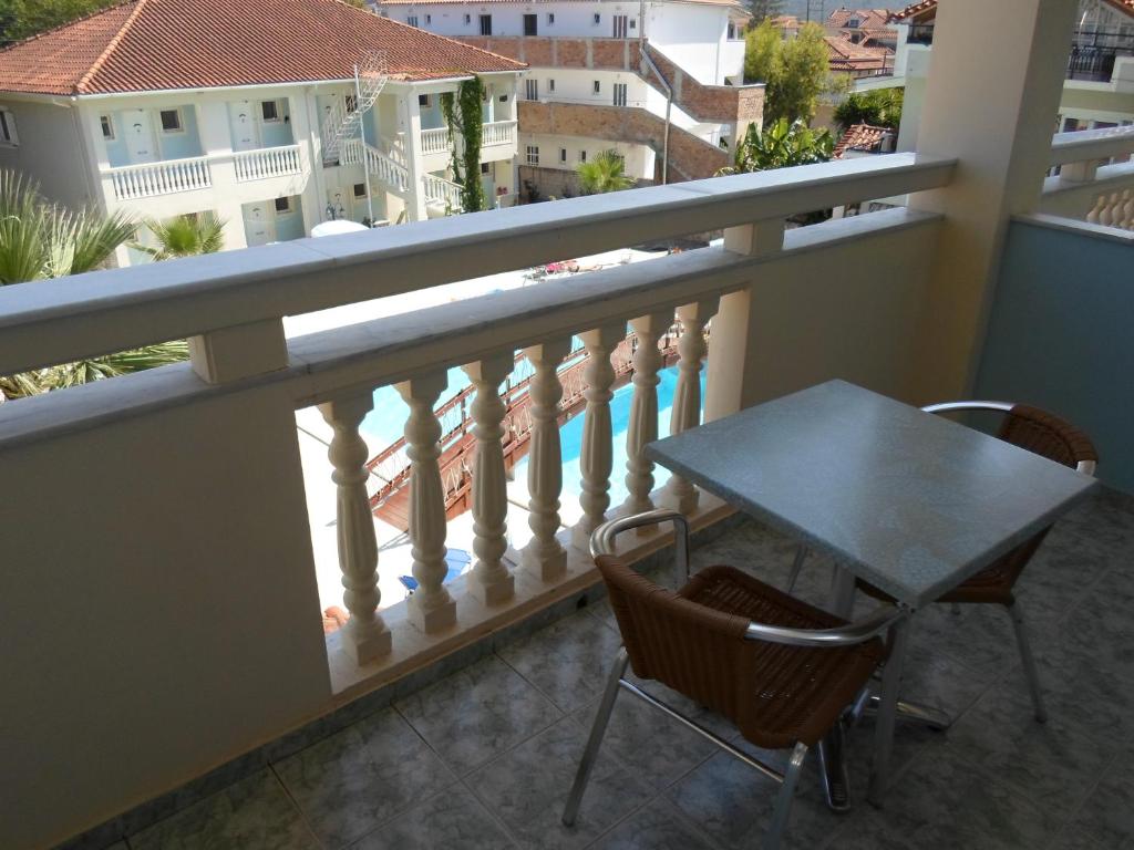a table and chairs on a balcony with a view of a pool at Hotel Villa Basil in Tsilivi