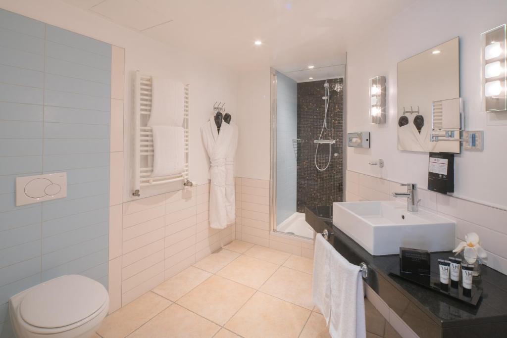 a white bathroom with a sink and a toilet at Best Western Plus Grand Hotel Victor Hugo in Luxembourg