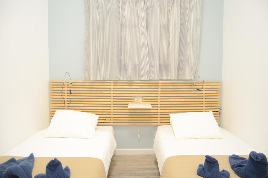 two beds in a room with a window at Apartamentos El Marinero - Roque in Caleta de Sebo
