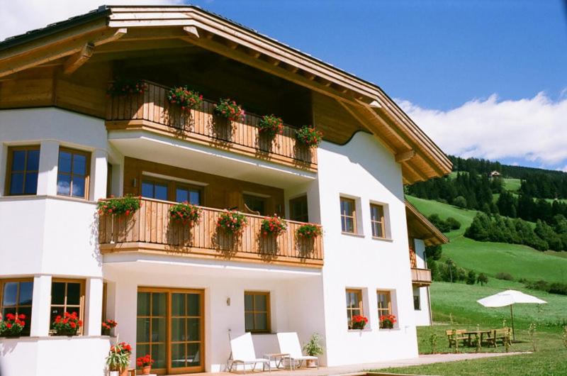 a large white house with a balcony with flowers at Appartements Josef Lercher in San Candido