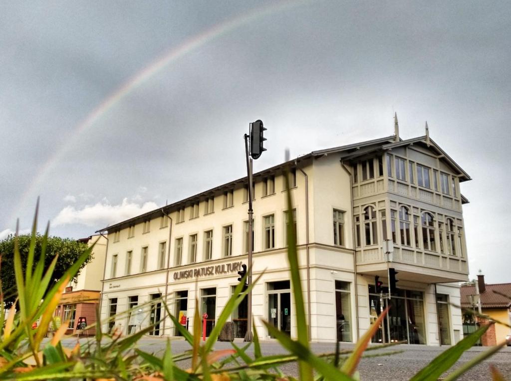 a rainbow in the sky above a white building at Ratusz B&B in Gdańsk
