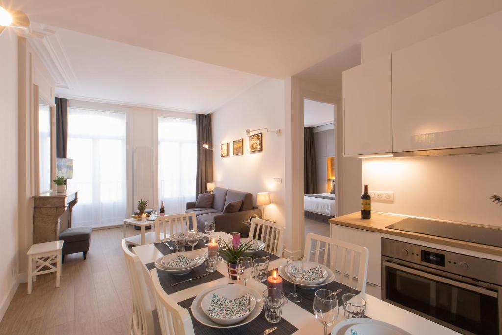 cocina y sala de estar con mesa y sillas en Arembault Appart Hôtel, en Lille