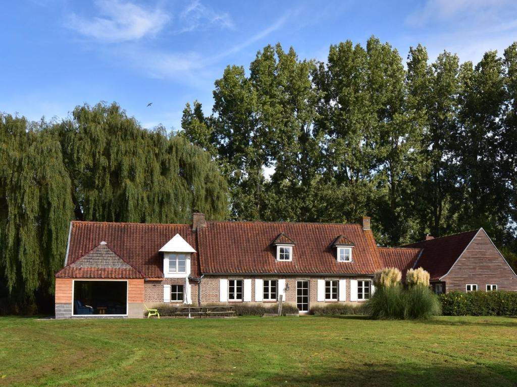 a house in a field with trees in the background at Beautiful holiday home with sauna in Saint-Omer