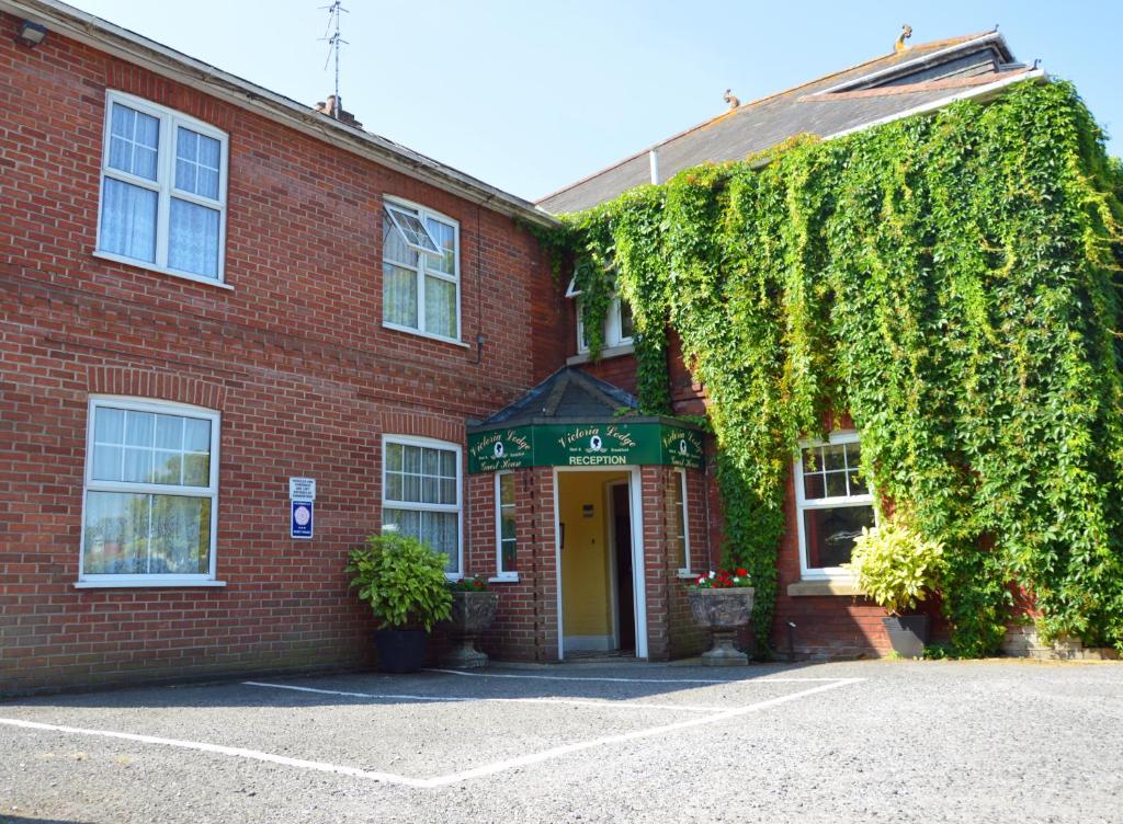 a red brick building with a yellow door at Victoria Lodge Guest House in Salisbury