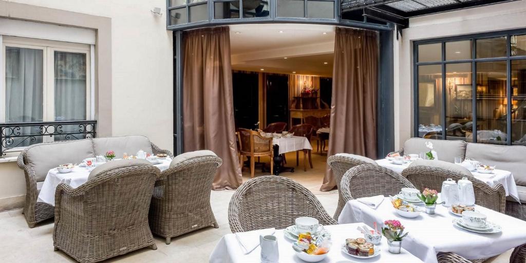 パリにあるオテル シャトーブリアンのテーブルと籐の椅子が付いたレストランを併設しています。
