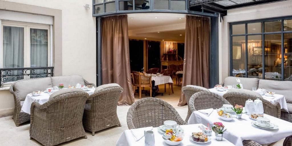 a restaurant with tables and wicker chairs with food on them at Hôtel Chateaubriand in Paris