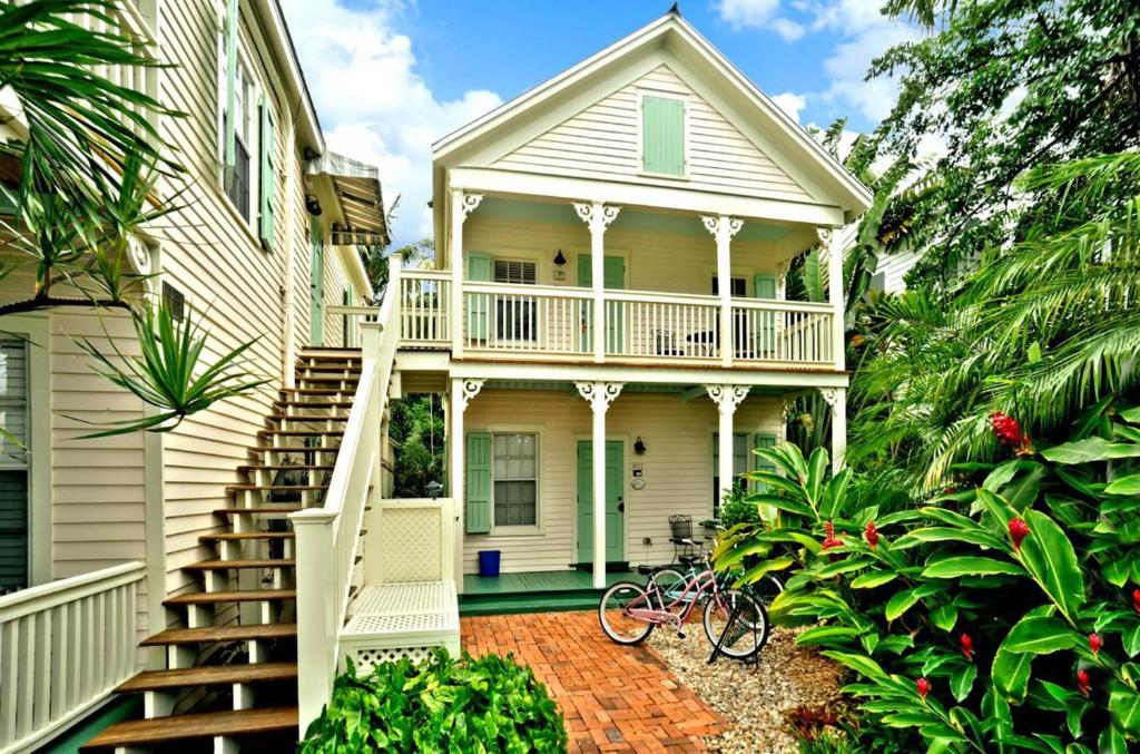 une maison blanche avec une terrasse couverte et un escalier dans l'établissement Palm Gardens, à Key West