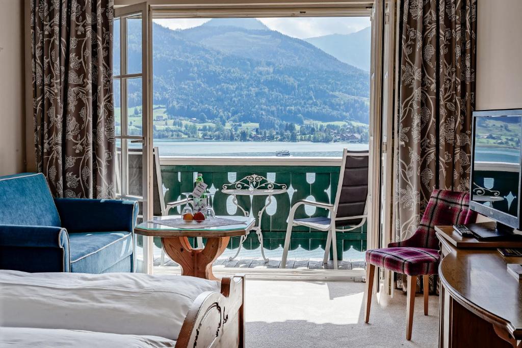 a room with a balcony with a view of the water at Hotel Peter in St. Wolfgang