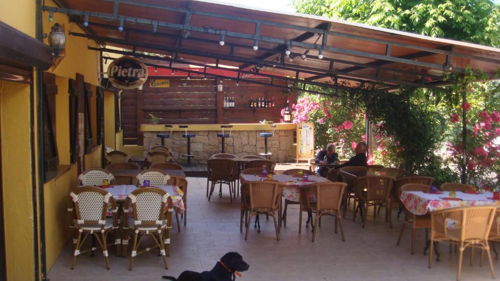 a dog sitting in front of a restaurant with tables and chairs at Le FLORIDA in Zicavo