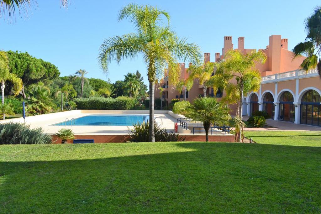 uma casa grande com piscina e palmeiras em Golf F5 by Garvetur em Vilamoura