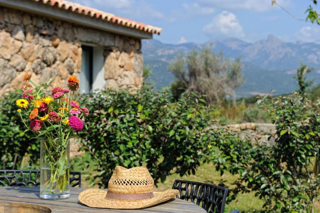 un sombrero sentado en una mesa con un jarrón de flores en Clos Simoni en Figari