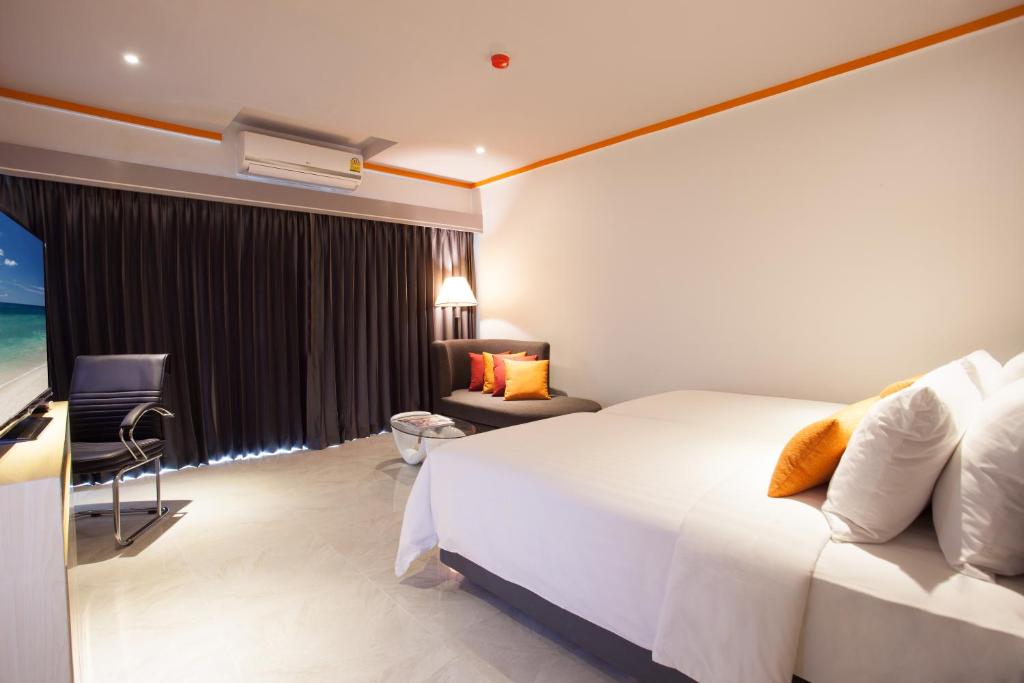 Pokój hotelowy z łóżkiem, krzesłem i oknem w obiekcie Chabana Kamala Hotel w mieście Kamala Beach