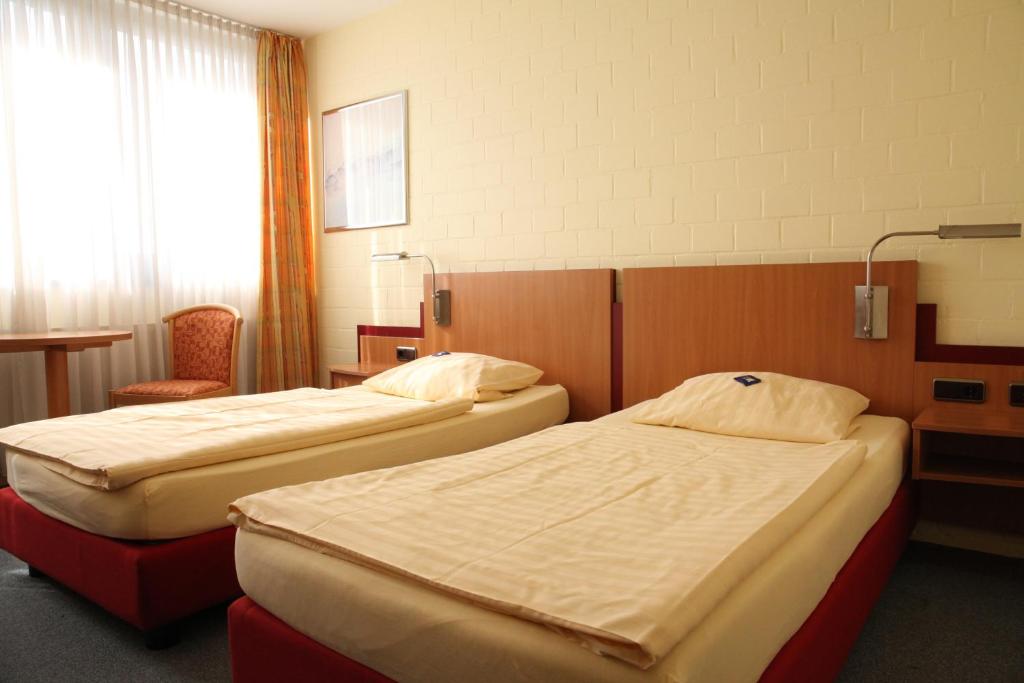 a room with two beds and a chair at RTB-Hotel - Sportschule in Bergisch Gladbach